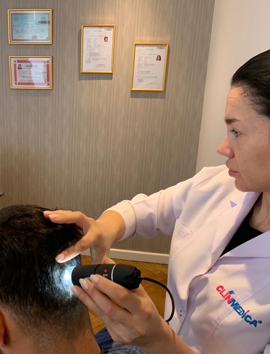 a woman using a light on a man's head Hair Transplant Turkey